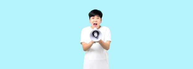 Foto tomboy asiático sobre fundo azul isolado gritando através de um megafone no estúdio com espaço de cópia