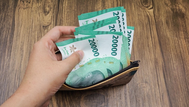 Tome a mano algo de dinero en rupias de una billetera batik Pague facturas y tome dinero de la billetera batik