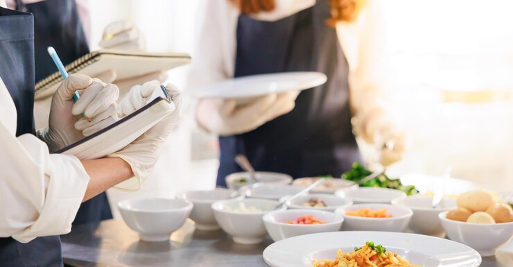 Tome nota en el libro Clase de cocina grupo de aulas culinarias de jóvenes estudiantes multiétnicas felices que se centran en lecciones de cocina en una escuela de cocina