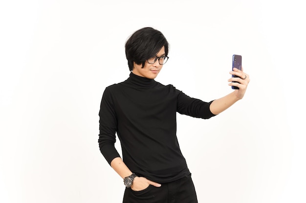 Tome un Selfie usando el teléfono inteligente de un hombre asiático guapo aislado en el fondo blanco