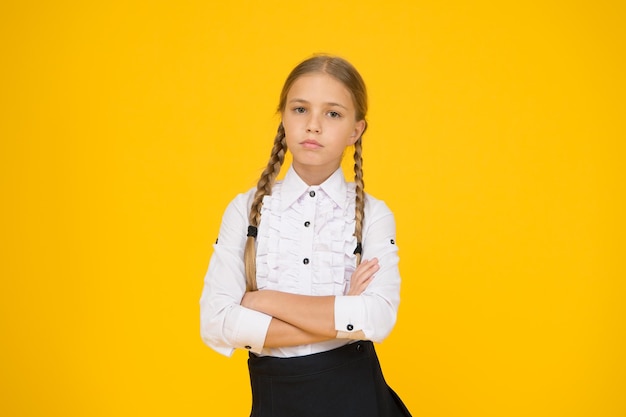 Tómese sus estudios en serio el concepto de educación moderna regreso a la escuela niña en uniforme niño después de las lecciones estudio en casa escuela estilo de moda estudiante de aspecto inteligente fondo amarillo