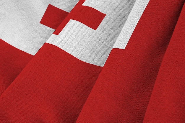 Tonga-Flagge mit großen Falten weht aus nächster Nähe unter dem Studiolicht im Innenbereich die offiziellen Symbole und Co