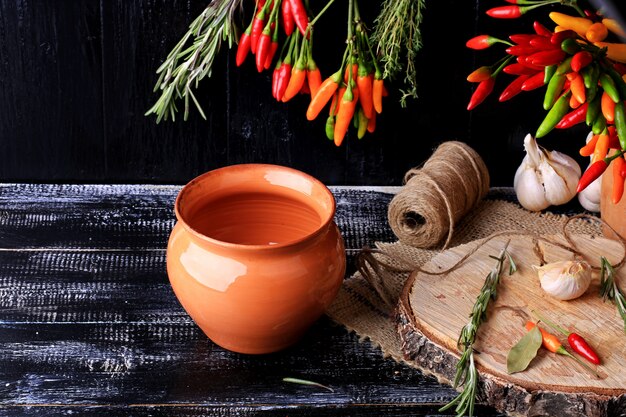 Tongefäß für das Rösten von Peperoni auf einem dunklen alten Holztisch würzt Retro- Weinleseart