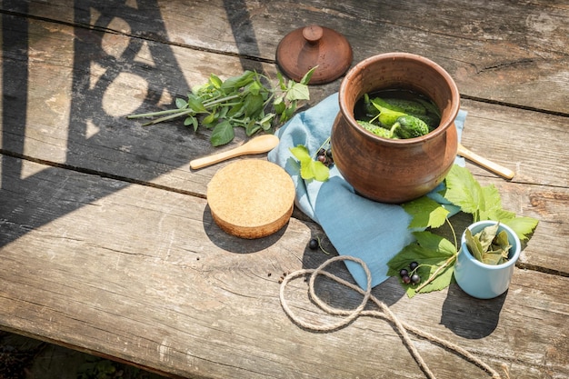 Tonglas mit natürlichen Gurken, schwarzen Johannisbeeren, Kräutern und Gewürzen auf einem Holztisch. Nachhaltige Lebensmittel