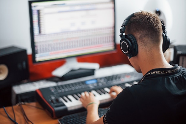 Foto toningenieur in kopfhörern, der im studio musik drinnen arbeitet und mischt.