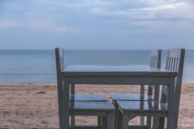 Tono vintage de mesa blanca para la cena en el fondo de la playa y el cielo