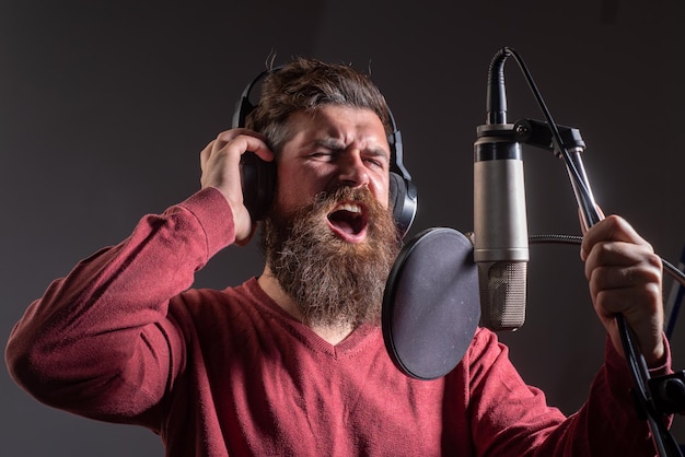 Tonproduzent Schöner Mann im Tonstudio Musikleistung Gesang Sänger singt Lied mit einem Mikrofon