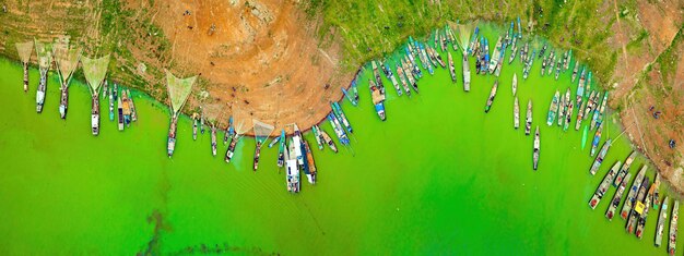 Top-Ansicht des Fischerdorfes Ben Nom frisches grünes Bild der grünen Algen-Saison am See Tri An mit vielen traditionellen Fischerschiffen, die in Dong Nai Vietnam verankert sind