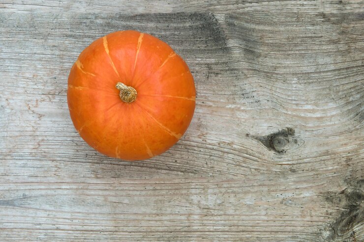 Foto top-ansicht des kürbisses roter kuri-kürbis hokkaido auf einem alten unbemalten tisch aus holz