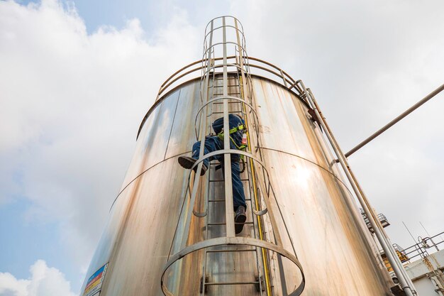 Top-Ansicht männlicher Arbeiter klettert auf die Leiter Inspektion Edelstahl-Tank Arbeit in der Höhe