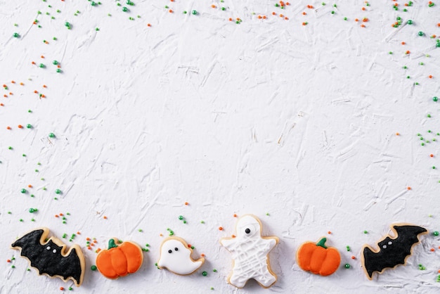 Foto top-ansicht von halloween festlich geschmückten glasur lebkuchen zucker kekse auf weißem hintergrund mit kopierraum und flachen layout
