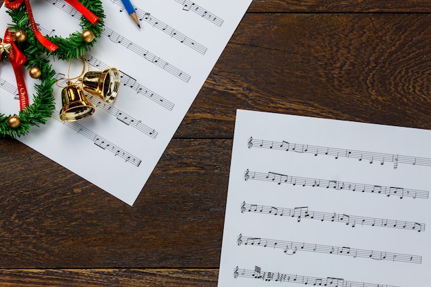 Top-Ansicht Weihnachtsmusik Notizpapier mit Weihnachtskranz auf Holzuntergrund und Kopie Raum.