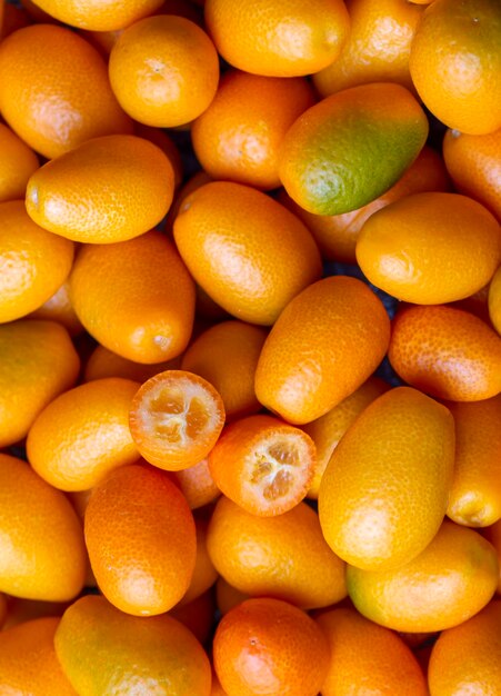 Foto top-aufnahme eines bündels frischer kumquats auf dem bio-lebensmittelmarkt einige kumquats sind geschnitten