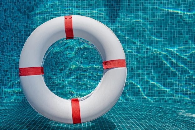 Top-Aussicht der Rettungsboje, die auf dem sonnigen blauen Wasser im Schwimmbad schwimmt