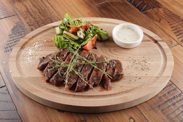Top-Blade-Steak mit Salat und Sauce. Hölzerner Hintergrund
