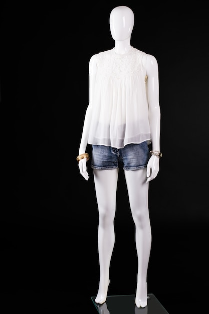 Top blanco y pantalones cortos de mezclilla. Maniquí de mujer en top blanco. Traje de verano sobre fondo oscuro. Aspecto elegante de la señorita.