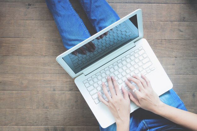 Top Blick auf Frau mit Laptop sitzen auf Holzboden, Lifestyle-Konzept mit Kopie Raum