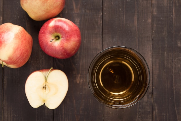 Top gesundes Apfelsaftgetränk und rote Apfelfrüchte auf Holz