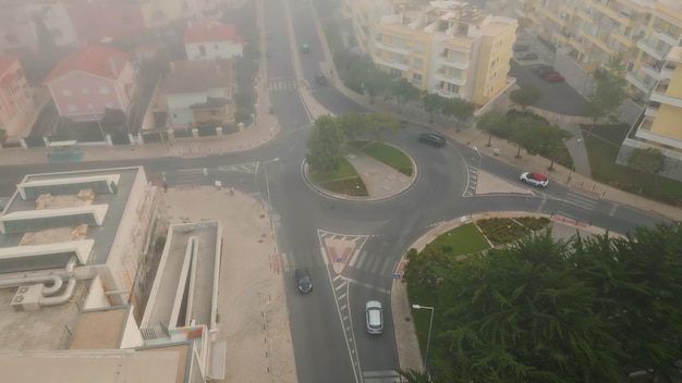 Top kleiner städtischer Kreisverkehr im Bezirk, der von Herbstnebel bedeckt ist, Autos fahren auf der Straße