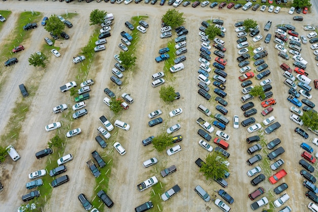 Top-Luftbild der Autoauktion viele Gebrauchtwagenparkplätze, die auf einem Parkplatz verteilt geparkt sind.