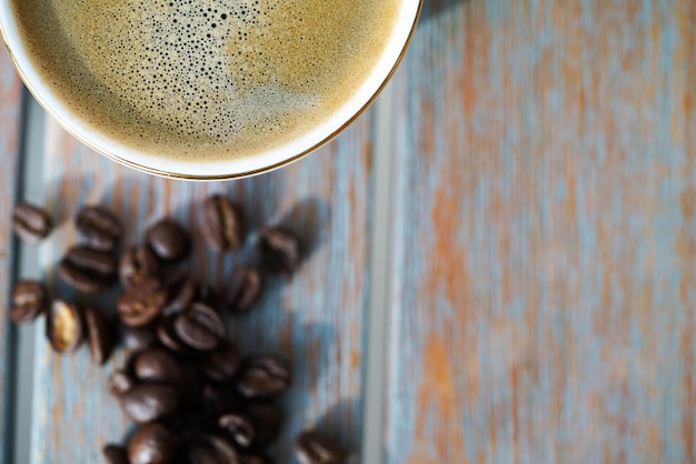 Foto top-view auf einer tasse kaffee mit schaum und kaffeebohnen auf einem holztisch