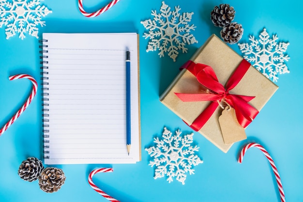Top view caixa de presente marrom, caderno e decoração de natal para o ano novo em cor pastel azul.