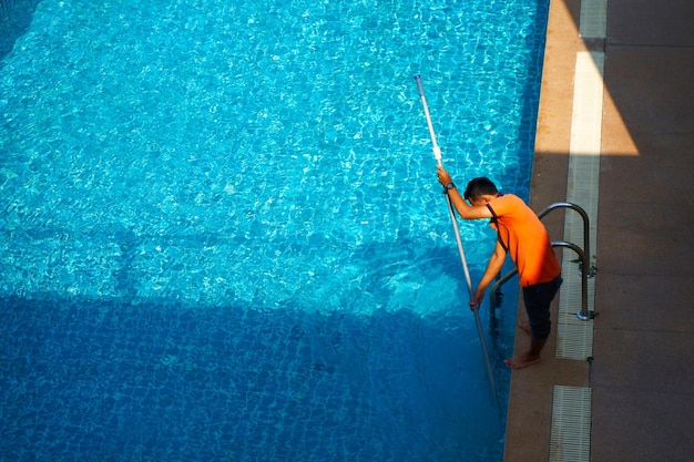 Top-View eines Arbeiters, der im Sommer ein Schwimmbad in einem Privathaus reinigt