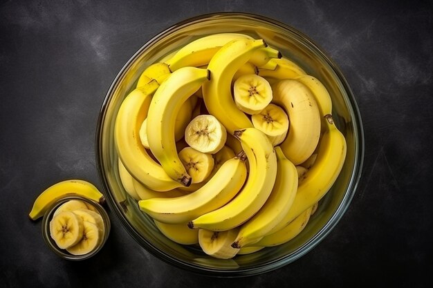 Foto top view fonte de nutrição bananas frescas agrupadas e picadas em uma panela de vidro em fundo cinza