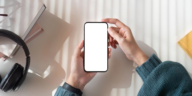 Top-View-Mockup-Bild einer Frau mit einem Handy mit leerem weißen Bildschirm, während sie sitzt.
