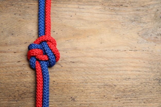 Foto top view of colorful ropes tied together on wooden background space for text unity concept