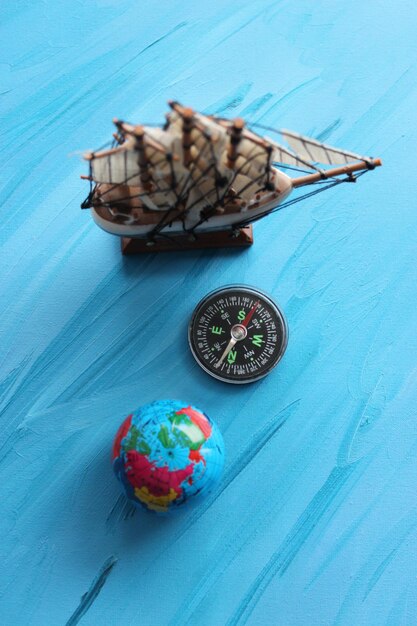 Top View Of Wooden Sailing Ship Mockup Compass And Globe On Painted Sea Surface Vertical Stock Phot (Visão superior de uma maqueta de navio a vela de madeira, bússola e globo na superfície pintada do mar)