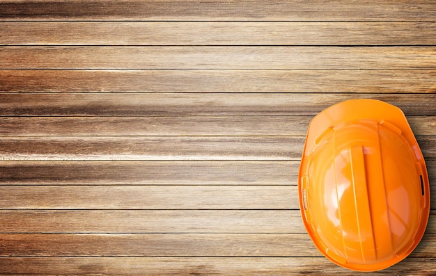 Top view orange Sicherheitshelmvon braunem Holz Tischhintergrund mit Kopierraum