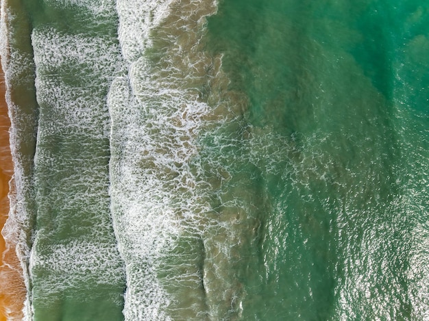 Foto top-view-strand mit wellen, die auf den sandstrand stürzen