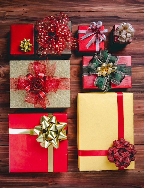 Top View Studio Shot Muster aus buntem Papier verpackt Geschenkboxen mit gold-rot-grün und silber glänzend glänzenden Bandfliege ordentlich auf dunkelbraunem Holztisch in Geburtstags- oder Weihnachtsfeier platziert.