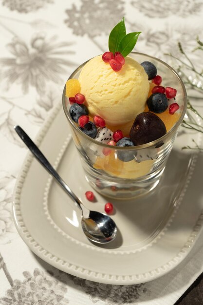 Top-View Vanille-Eis in Glas, mit gemischten Früchten und geschmückt mit kleinen Blättern