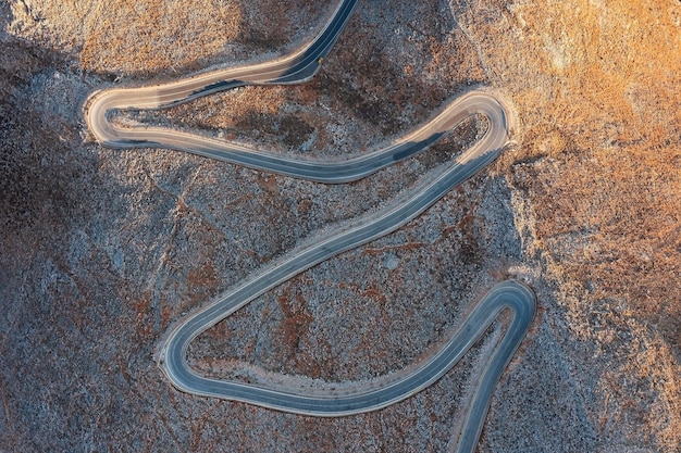 Topdown-Luftbild einer kurvenreichen Straße im Wüstenhochland bei Sonnenuntergang Kreta Griechenland