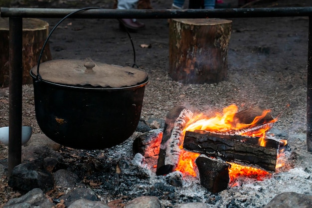 Topf in Flammen. Wasserkocher mit Wasser oder Tee am Feuer, Touristen einen Wasserkocher am Feuer. Campingfoto