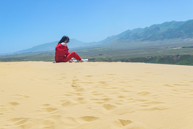 Topo da duna de areia Sarykum no Daguestão, um lagarto entre a areia e uma turista feminina turva ao fundo