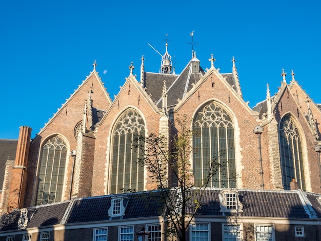 Foto topo da igreja velha (oude kerk) no principal distrito da luz vermelha em amsterdã, holanda, sob céu azul