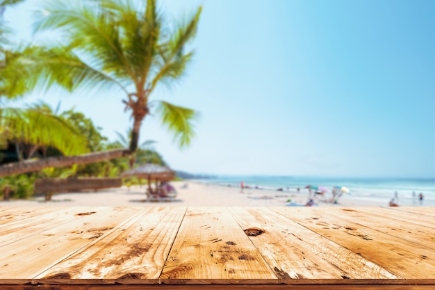 Foto topo da mesa de madeira com vista do mar, palmeira, mar calmo e céu na praia tropical