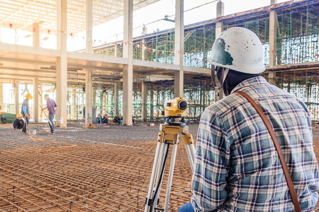 El topógrafo realiza mediciones con equipos de teodolito en el sitio de construcción de la fábrica.