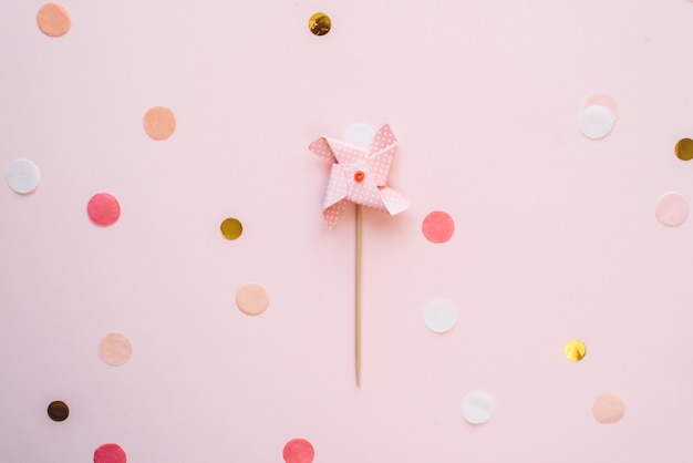 Topper de veleta en colores pastel para niños para un cupcake sobre un fondo rosa con confeti. Fondo festivo de cumpleaños