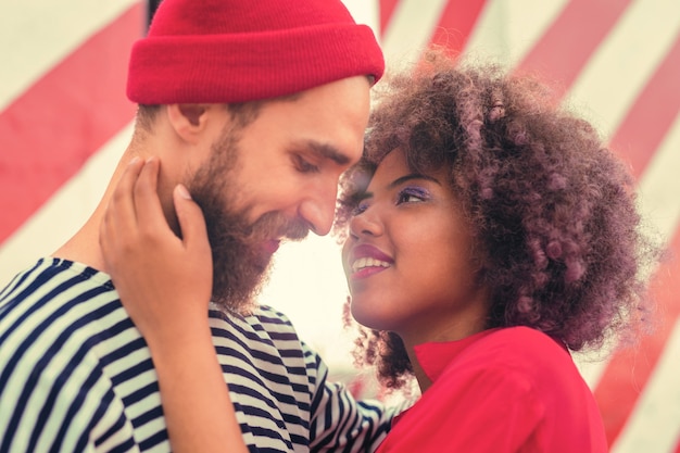 Toque romântico. Mulher jovem e bonita se sentindo feliz e sorrindo para seu amável namorado barbudo enquanto toca seu rosto