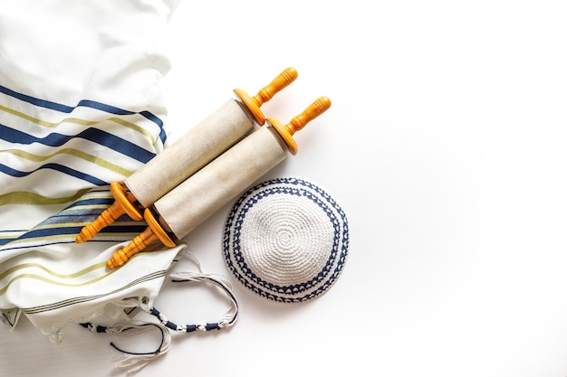 Foto torah-schriftrolle mit einem zeiger gebetsschal tallit und kippa auf einem hellen hintergrund