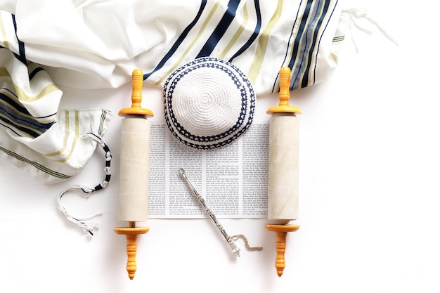 Torah-Schriftrolle mit einem Zeiger Gebetsschal Tallit und Kippa auf einem hellen Hintergrund