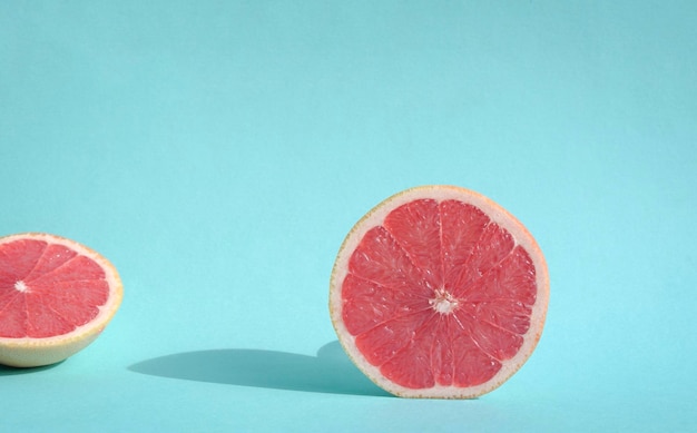 Toranja fresca cortada na luz solar com sombras duras no fundo azul pastel