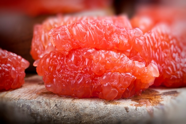 Toranja vermelha descascada dividida em fatias durante o cozimento, toranja cítrica suculenta