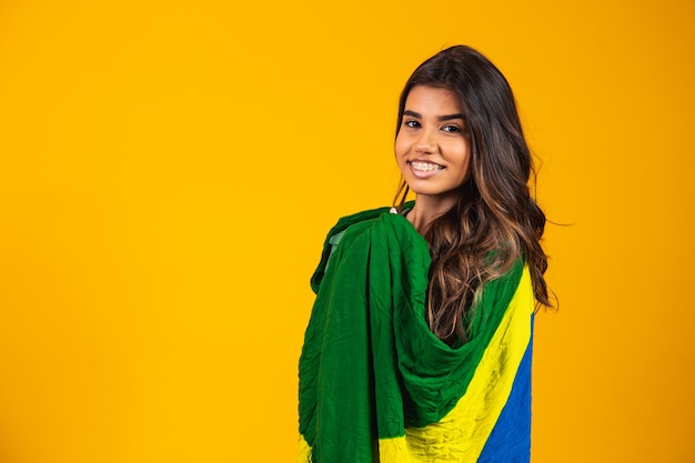 Torcedor brasileiro. Fã da mulher brasileira comemorando no futebol ou jogo de futebol em fundo amarelo. Cores do Brasil.