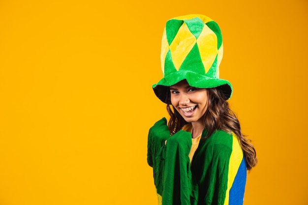 Torcedor brasileiro. Fã da mulher brasileira comemorando no futebol ou jogo de futebol em fundo amarelo. Cores do Brasil.