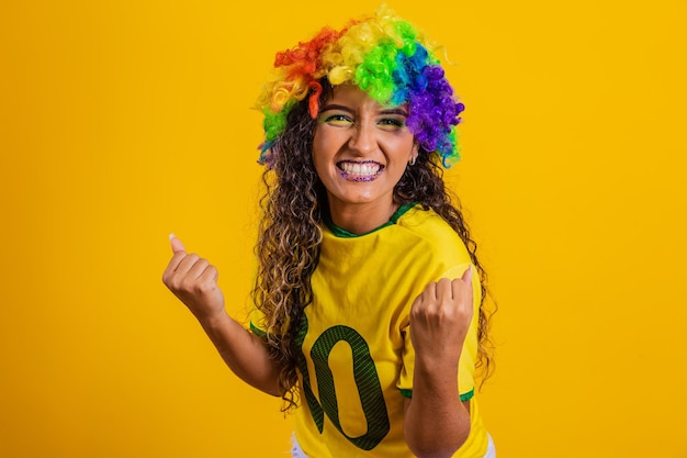 Torcedor brasileiro Fã de mulher brasileira comemorando no futebol ou jogo de futebol em fundo amarelo cores do Brasil